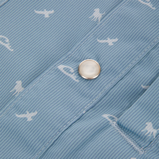 Close-up of Drake Cinco Ranch Western Short Sleeve Shirt, featuring light-blue striped fabric with white dinosaur silhouettes, metallic snap button, and edge of a stitched pocket.