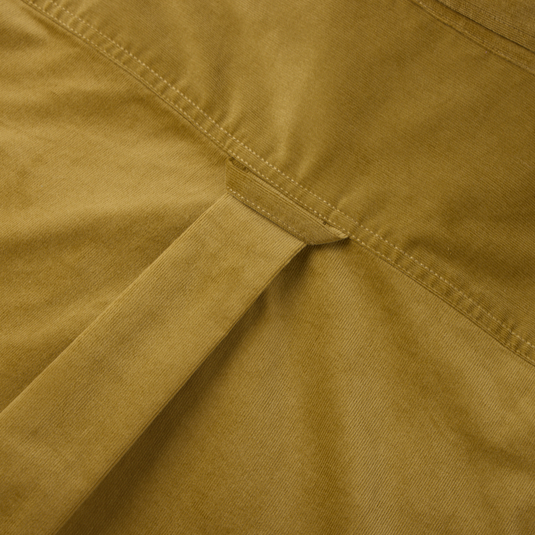 Close-up of a mustard-colored garment with a cinch strap, showcasing Drake's Midwale Corduroy Shirt featuring stretch fabric, button-down collar, and sculpted hem.