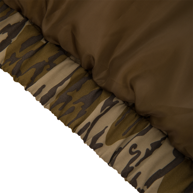 Close-up of the Throwback 80 Insulated Sport Bomber Jacket’s quilted panel, highlighting its olive-brown nylon shell and elastic camouflage hem, ideal for hunting adventures.
