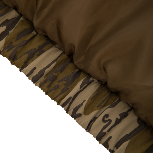 Close-up of the Throwback 80 Insulated Sport Bomber Jacket’s quilted panel, highlighting its olive-brown nylon shell and elastic camouflage hem, ideal for hunting adventures.