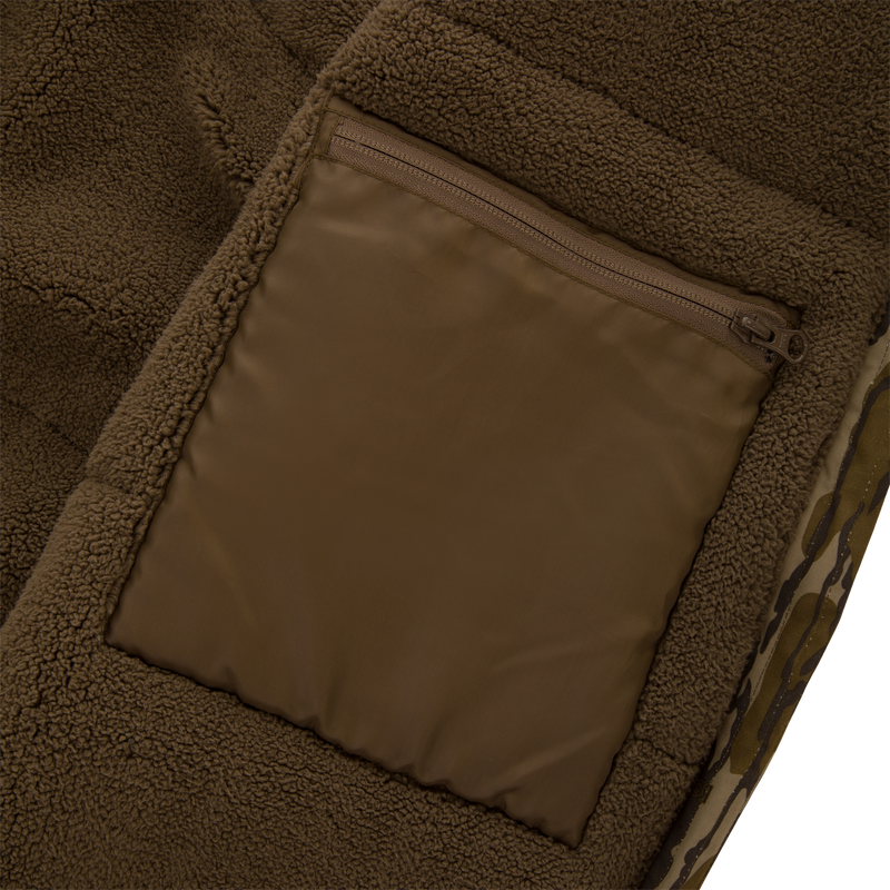 Close-up of the Throwback 80 Sport Vest's brown sherpa fleece with a zippered nylon pouch, showcasing its durable outdoor-ready design for hunting enthusiasts.