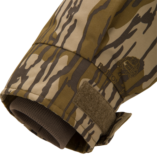 Close-up of the Throwback 80 Sport 3-in-1 Jacket's camo sleeve cuff, showing a tiger-stripe print, adjustable Velcro tab, and inner knit wrist gaiter.