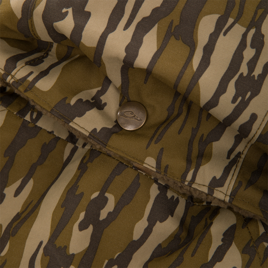 Close-up of the Throwback 80 Sport 3-in-1 Jacket, featuring tiger-stripe camo fabric, metal snap button, brown fleece lining, and detailed stitching on a pocket flap.