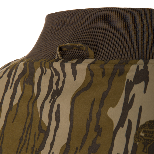 Close-up of the Throwback 80 Sport 3-in-1 Jacket's camo-patterned back, showcasing the ribbed knit collar and hanging loop, ideal for outdoor adventures.