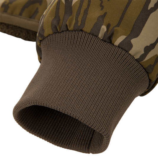 Close-up of a camo-patterned mitten's wrist area, showcasing the fleece lining and ribbed knit cuff, part of the Throwback 80 Sport 3-in-1 Jacket ensemble.