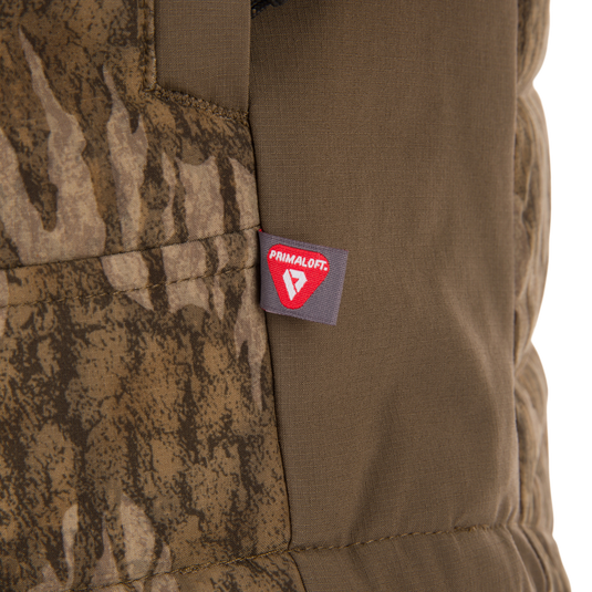 Close-up of LST BMF Jacket with Primaloft, showing a stitched tag on camouflage and olive-green fabric, highlighting its insulated, lightweight design for active use.
