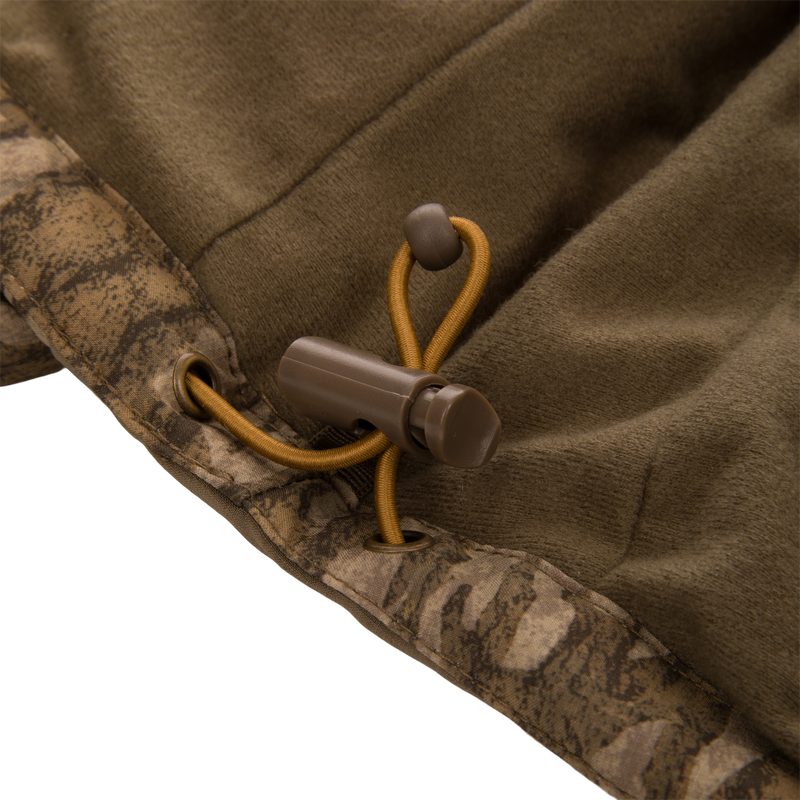 Draw-cord lock on the LST BMF Jacket with Primaloft, showcasing its adjustable hem with mustard-yellow elastic cord and camo-print binding for optimal outdoor adaptability.