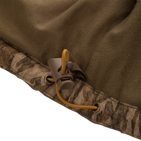 Close-up of LST BMF Vest hem, featuring an olive-brown and camo design with a tan drawcord and toggle, showcasing durable, water-resistant construction.