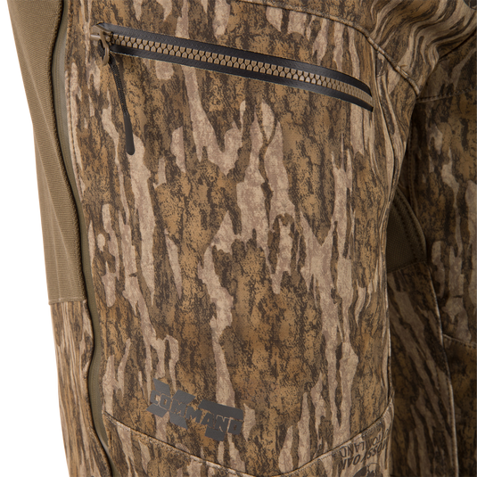 Close-up of the MST CommandXT Softshell Pant showcasing a zip-closed pocket with the COMMANDO logo on camouflage fabric, highlighting durability for demanding hunting activities.
