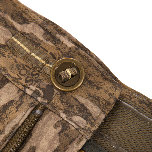 Close-up of the MST CommandXT Softshell Pant, featuring camo fabric, zipper, webbing with grommet, showcasing durability and flexibility for demanding outdoor activities.