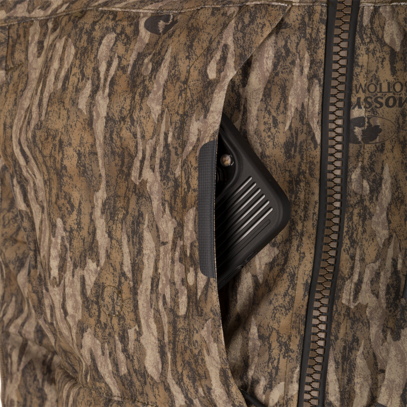 Front pocket of the LST CommandXT 3-in-1 PrimaLoft Insulated Jacket, showing a black electronic device with a lens and ridged sides.