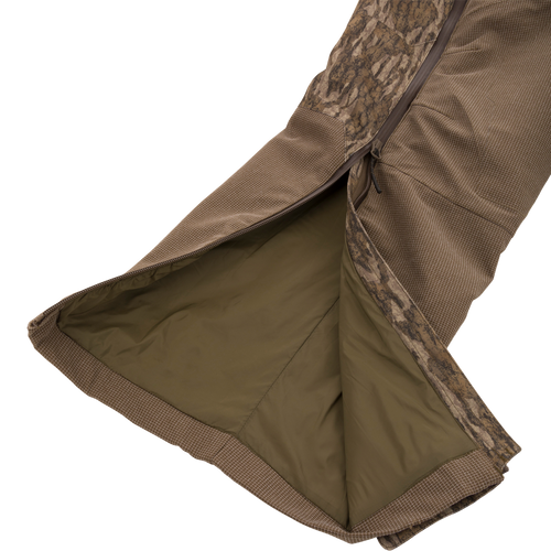 LST CommandXT Bib with Primaloft shown with camo shell, revealing olive lining and side zipper, highlighting its warmth and durability for extreme hunting conditions.