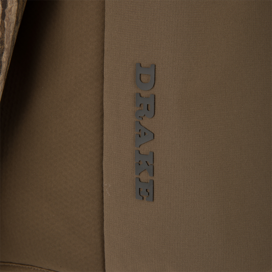 Close-up of LST BMF Eqwader Half Zip Jacket by Drake, showcasing two-tone brown fabric with DRAKE branding, highlighting its durable, waterproof, and insulated design.