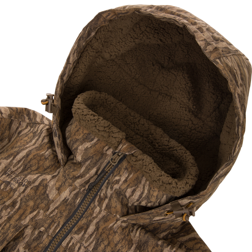 LST BMF Eqwader Half Zip Jacket with Primaloft, featuring camo-pattern, sherpa-lined hood, front zipper, and hood-adjustment toggles, designed for warmth and functionality in outdoor conditions.