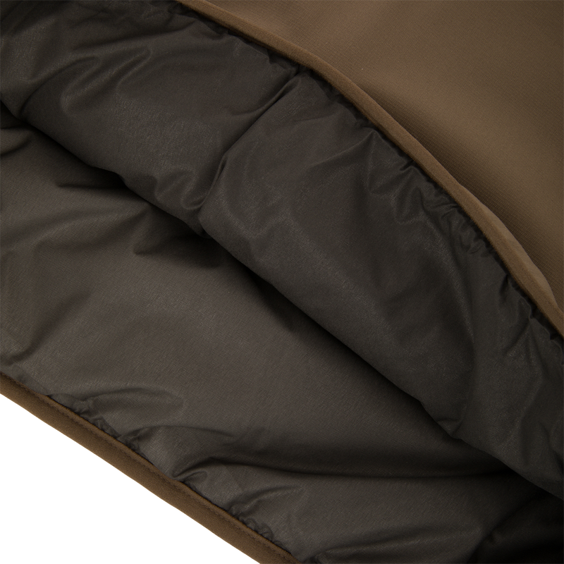 Close-up of the LST BMF Eqwader Half Zip Jacket showing its brown shell and quilted insulated lining for warmth and protection in harsh weather.