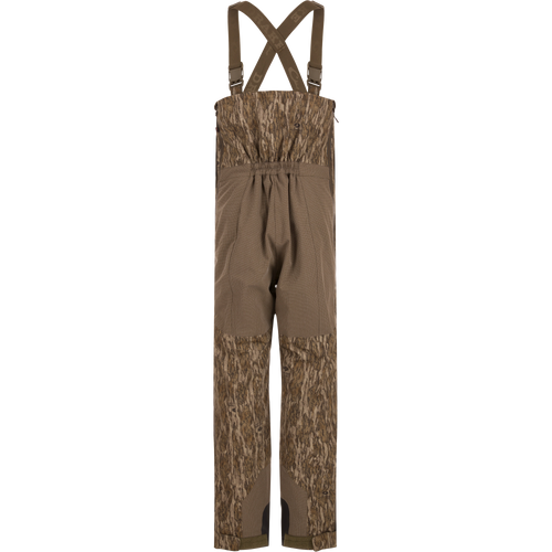 LST BMF Pit Bib with Primaloft: Camouflage bib pants featuring wood-grain camo, reinforced knee/seat panels, adjustable suspenders, and full-length zippers, ideal for rugged hunting conditions.