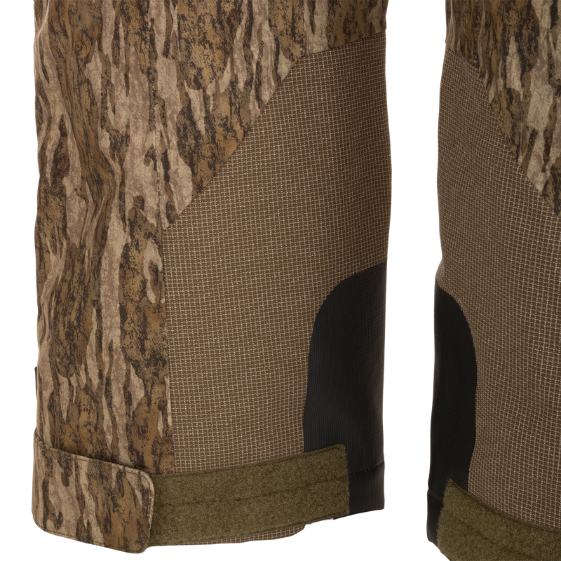 Close-up of LST BMF Pit Bib ankle cuffs, showcasing camo panels, grid-pattern reinforcements, abrasion-resistant patches, and adjustable straps for secure boot fit.