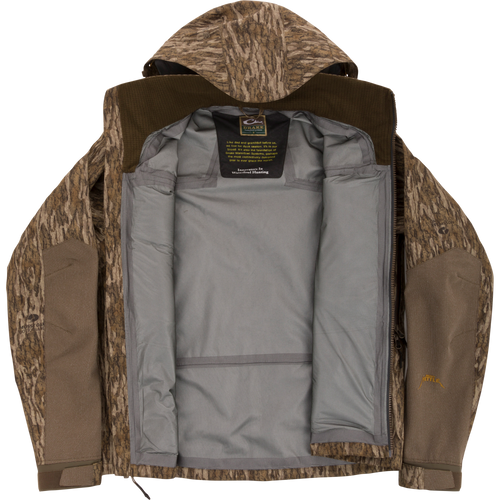 Purewhitelaneshop LST BMF Pit Jacket with camo exterior, unzipped to show gray lining and label. Designed for extreme conditions with durable, weather-resistant features.