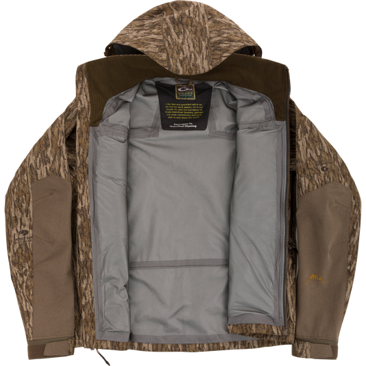 Purewhitelaneshop LST BMF Pit Jacket with camo exterior, unzipped to show gray lining and label. Designed for extreme conditions with durable, weather-resistant features.