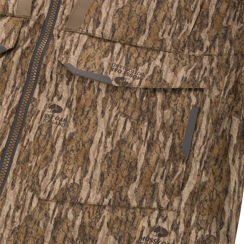 Close-up of the LST BMF Pit Jacket showcasing its Mossy Oak Bottomland camouflage pattern, front zipper, and Velcro-flap pockets, designed for extreme hunting conditions.
