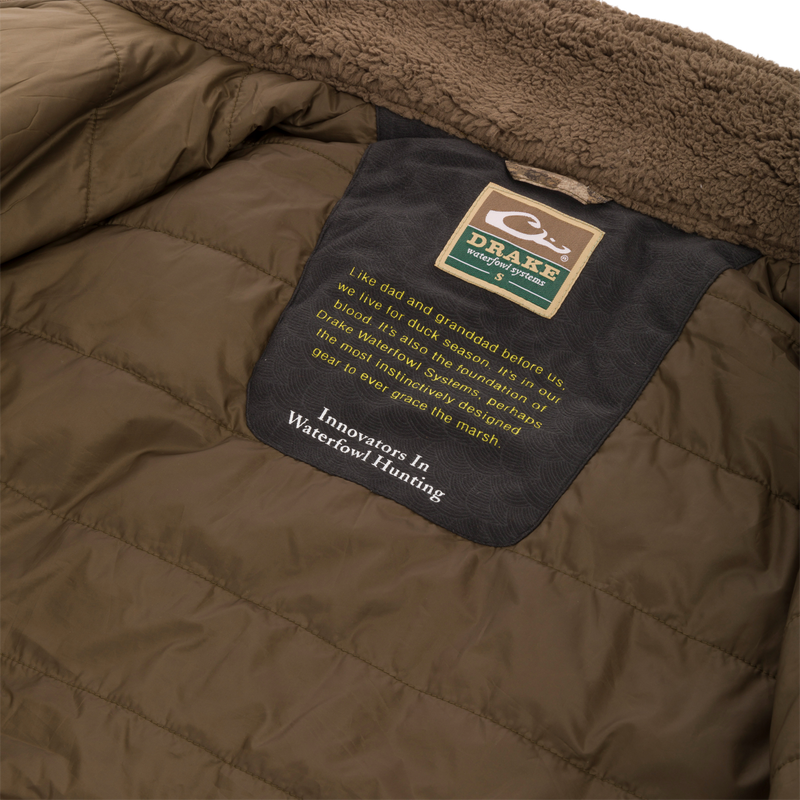 Close-up of the LST BMF 3-in-1 Pit Jacket's interior, highlighting the shearling-lined collar and Purewhitelaneshop Systems label with an inspiring message about duck hunting heritage.