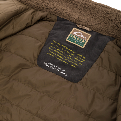 Close-up of the LST BMF 3-in-1 Pit Jacket's interior, highlighting the shearling-lined collar and Purewhitelaneshop Systems label with an inspiring message about duck hunting heritage.