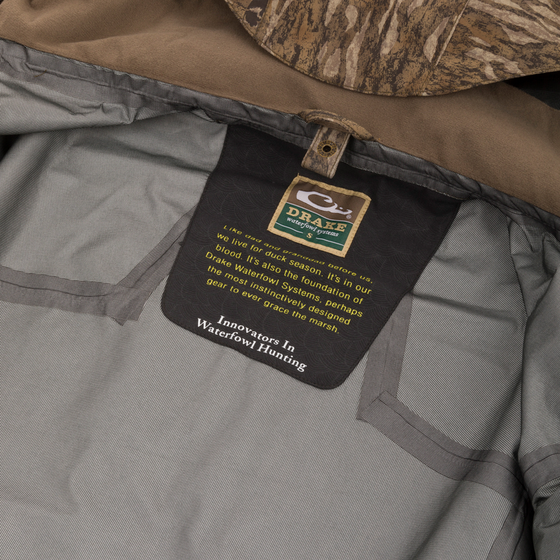 Inside view of the LST BMF 3-in-1 Pit Jacket with Primaloft, showcasing branding, durable materials, and camo-patterned hood edge for versatile hunting protection.