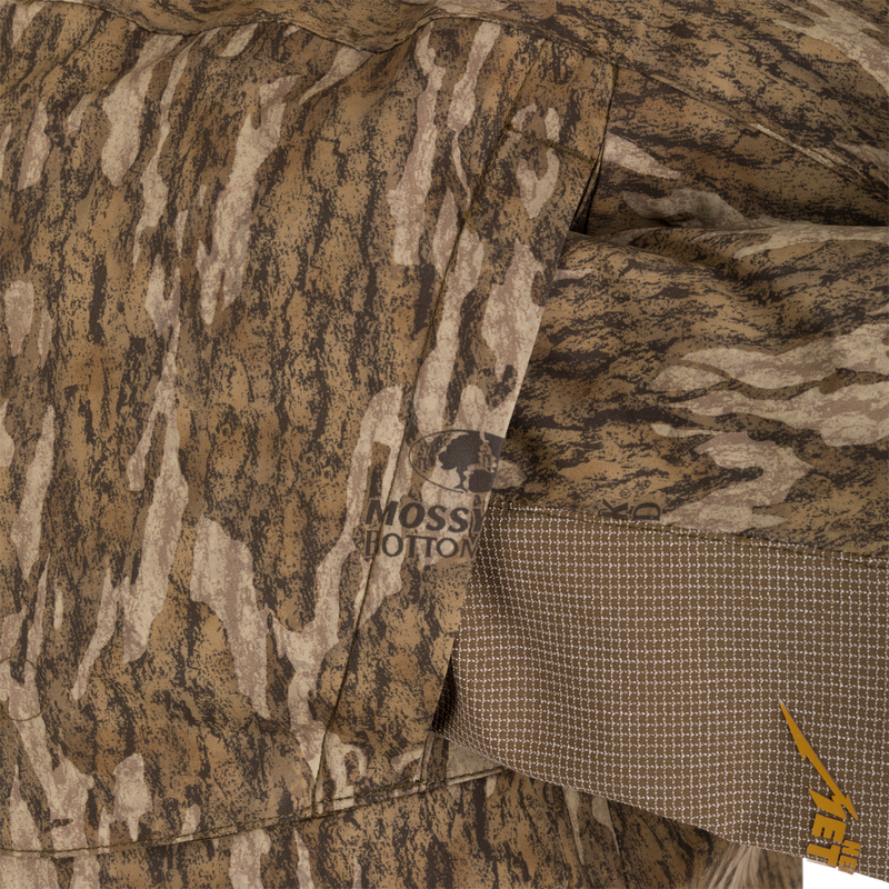 Close-up of the LST BMF 3-in-1 Pit Jacket with Primaloft, showcasing Mossy Oak Bottomland camo pattern, stitched pocket, and YETI logo.