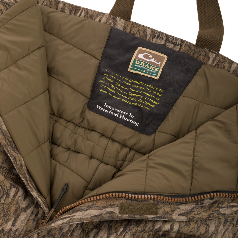 Purewhitelaneshop Systems label inside the LST Hardline Insulated Bib, highlighting durable, insulated, camo-patterned construction with advanced weather protection features for waterfowl hunting.