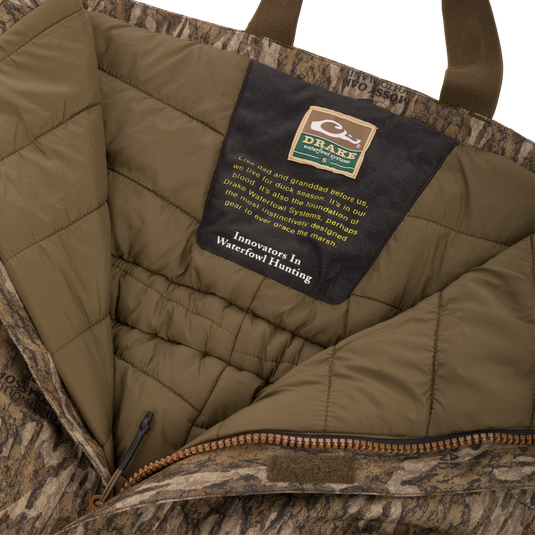 Purewhitelaneshop Systems label inside the LST Hardline Insulated Bib, highlighting durable, insulated, camo-patterned construction with advanced weather protection features for waterfowl hunting.