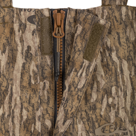 Close-up of the LST Hardline Insulated Bib, featuring a central heavy-duty zipper, hook-and-loop storm flap, and tree-bark camouflage fabric for superior warmth and protection.