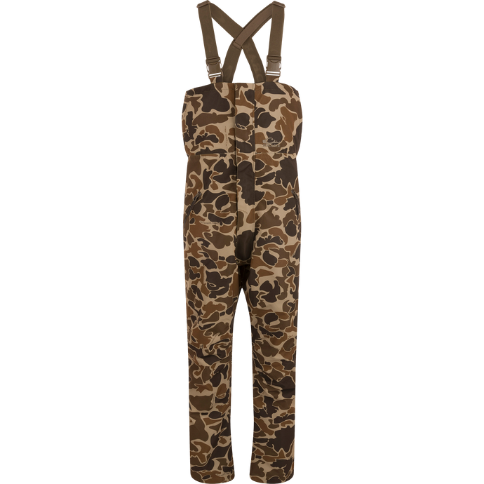 LST Hardline Insulated Bib with camo pattern, adjustable suspenders, and storm-resistant zippers, designed for warmth and mobility in harsh outdoor conditions.