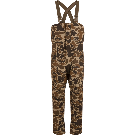 LST Hardline Insulated Bib with camo pattern, adjustable suspenders, and storm-resistant zippers, designed for warmth and mobility in harsh outdoor conditions.