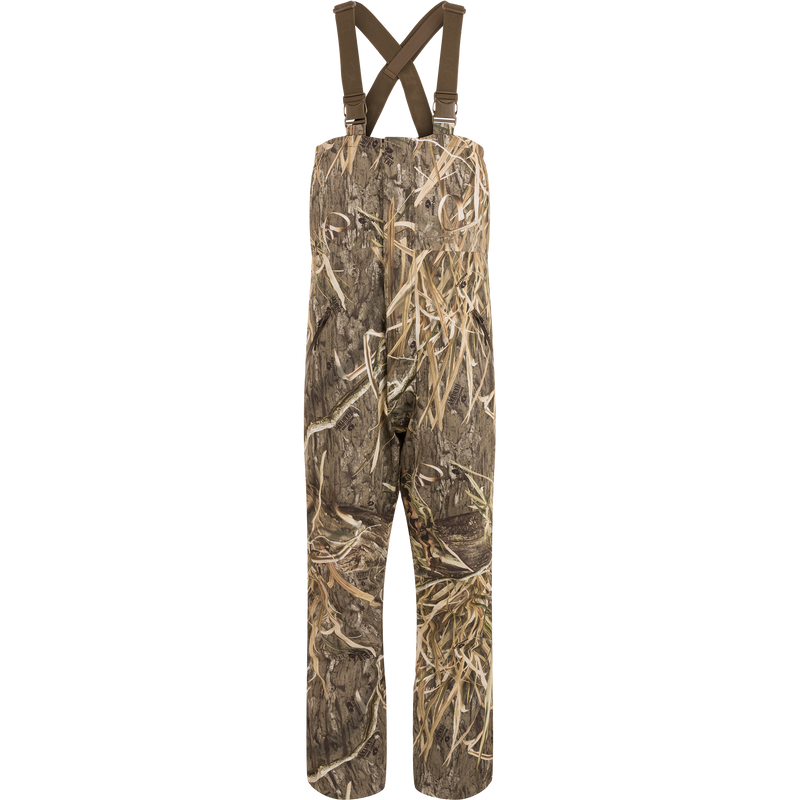 LST Hardline Insulated Bib: Camouflage overalls with adjustable straps, durable waterproof polyester, insulated for warmth, featuring handwarmer pockets, storm flaps, and articulated knees for hunting.