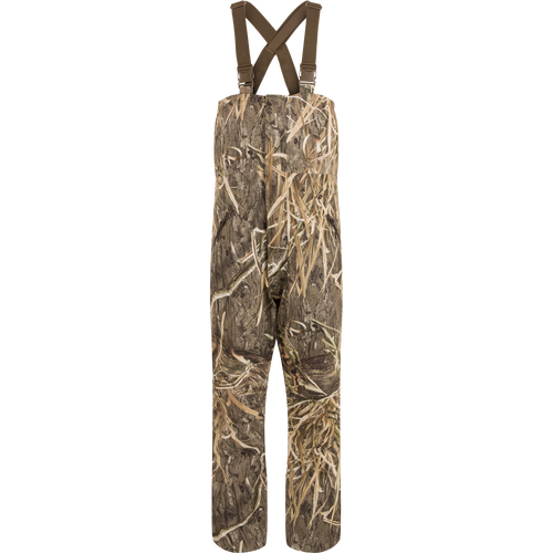 LST Hardline Insulated Bib: Camouflage overalls with adjustable straps, durable waterproof polyester, insulated for warmth, featuring handwarmer pockets, storm flaps, and articulated knees for hunting.