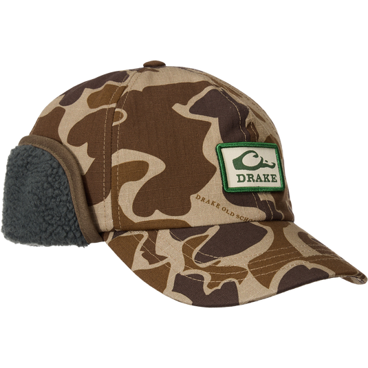 Camo-patterned MST Flap Cap with fold-down fleece ear flaps, featuring a duck graphic patch and adjustable clasp, designed for outdoor warmth and comfort.
