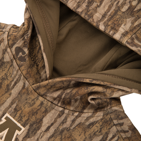 Youth Performance Hoodie in camouflage with an olive-lined hood, showcasing a stitched M on the chest and a kangaroo pocket, designed for young athletes' comfort and versatility.