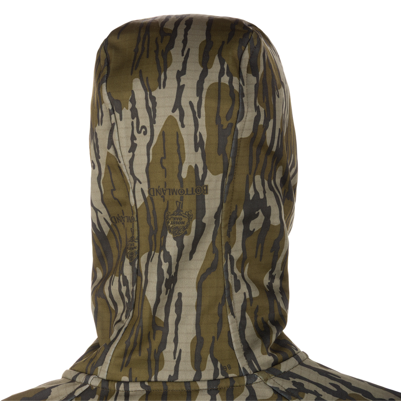 Grid Fleece Half Zip Hoodie in Bottomland Mossy Oak camo, showing back, hood, and faint logo. Features include moisture-wicking grid-fleece, stretch fabric, and water-resistant pocket.