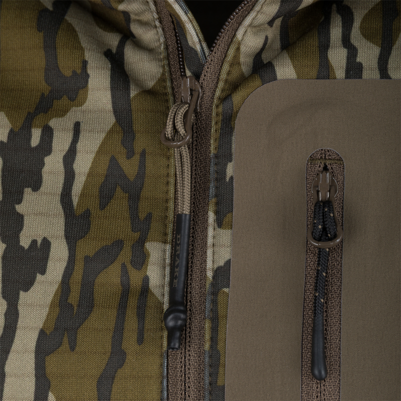 Close-up of Purewhitelaneshop's Grid Fleece Half Zip Hoodie, highlighting camo fabric, main zipper with corded pull, and water-resistant chest pocket with branded pull.