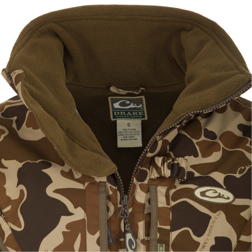 Close-up of the MST Waterproof Fleece-Lined Quarter Zip Jacket with Drake label, showcasing camouflage shell, olive fleece lining, and central zipper.