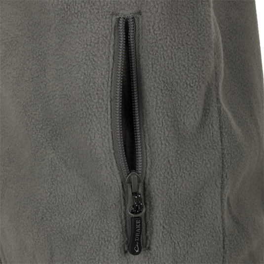 A close-up of the zipper on the Youth Camp Fleece Vest, a durable and comfortable 100% Polyester vest with anti-pill treatment, moisture-wicking properties, and zippered handwarmer pockets.