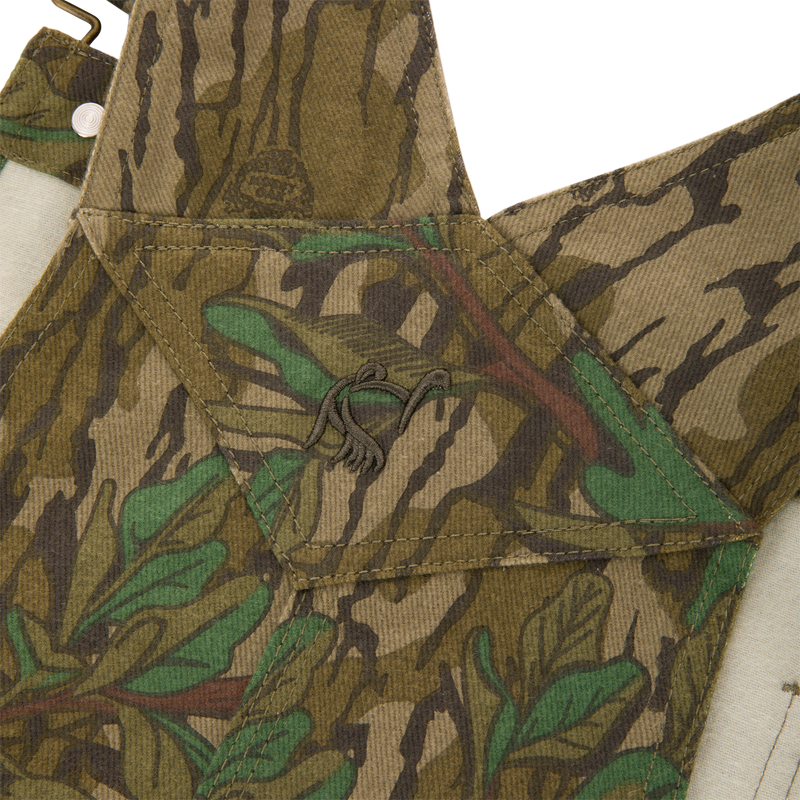 Throwback 80 Field Bib, featuring a camouflage pattern, durable triple stitching, antique brass details, and reinforced knees, ideal for tough outdoor activities.