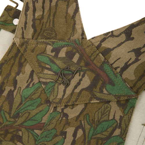 Throwback 80 Field Bib, featuring a camouflage pattern, durable triple stitching, antique brass details, and reinforced knees, ideal for tough outdoor activities.