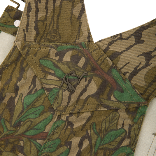 Throwback 80 Field Bib, featuring a camouflage pattern, durable triple stitching, antique brass details, and reinforced knees, ideal for tough outdoor activities.