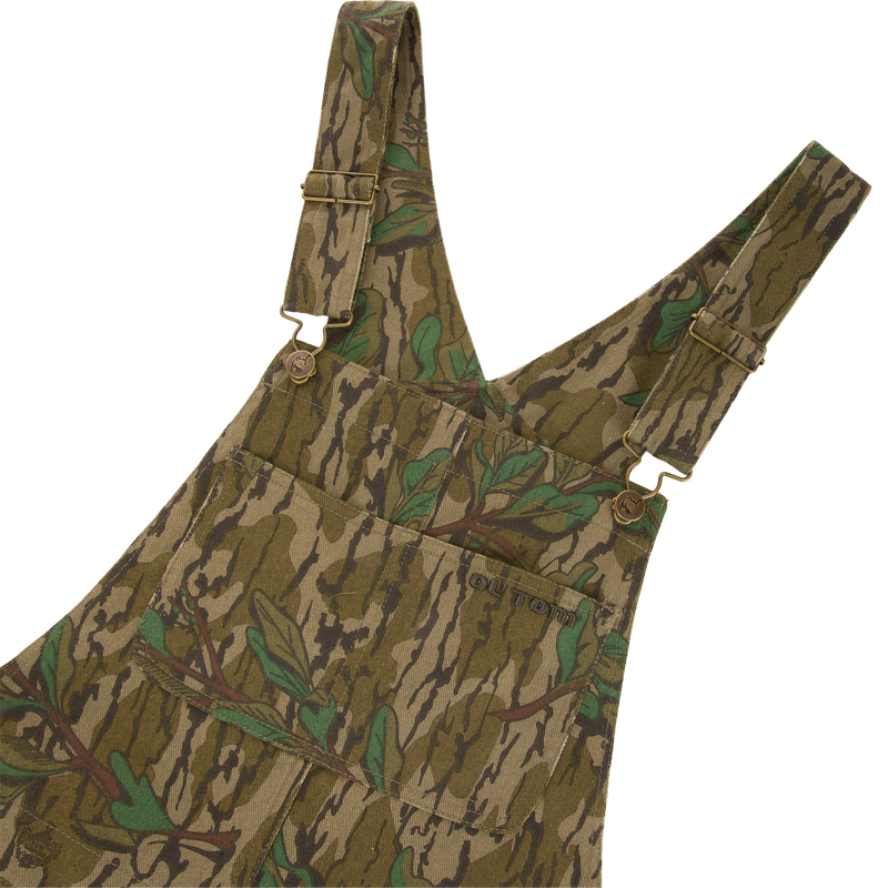 Throwback 80 Field Bib featuring camouflage design, metal button details, triple needle stitching, and reinforced knees, ideal for durable use in demanding hunting environments.