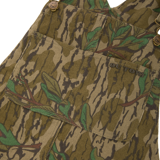 Throwback 80 Field Bib, camouflage overall, showcasing durable cotton twill, antique brass details, and reinforced knees, ideal for hunting and rugged tasks.