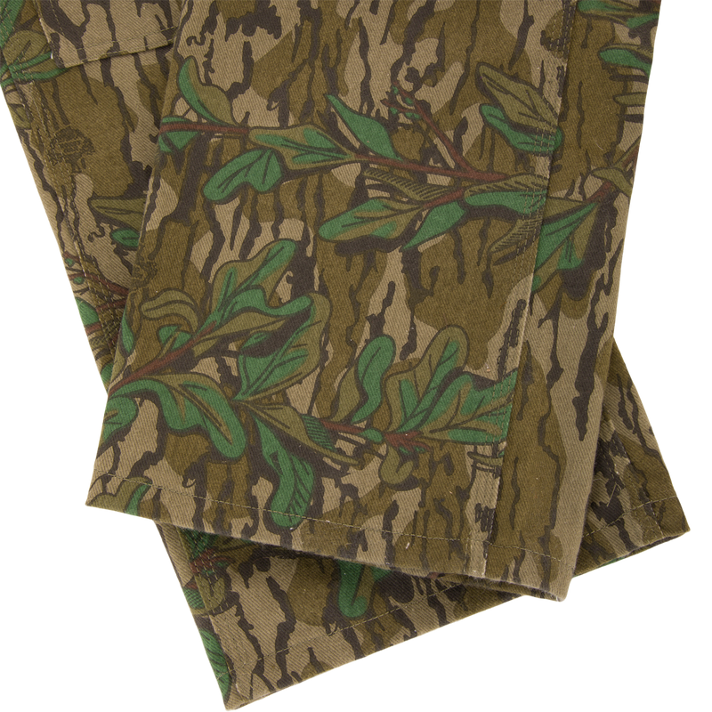 Throwback 80 Field Bib, featuring durable cotton twill with a camouflage pattern, triple needle stitching, and antique brass accents, ideal for tough outdoor tasks.