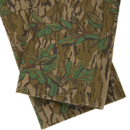 Throwback 80 Field Bib, featuring durable cotton twill with a camouflage pattern, triple needle stitching, and antique brass accents, ideal for tough outdoor tasks.