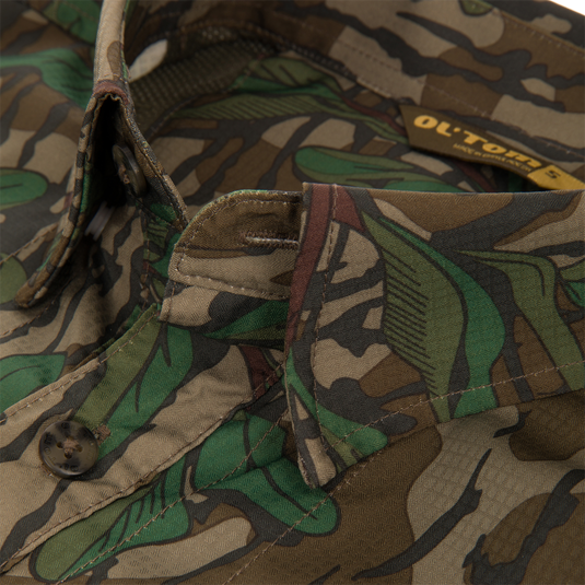 Men's Camo Wingshooter Trey Shirt close-up, featuring camouflage fabric, hidden button-down collar, vented cape back, and button-through flap chest pockets.