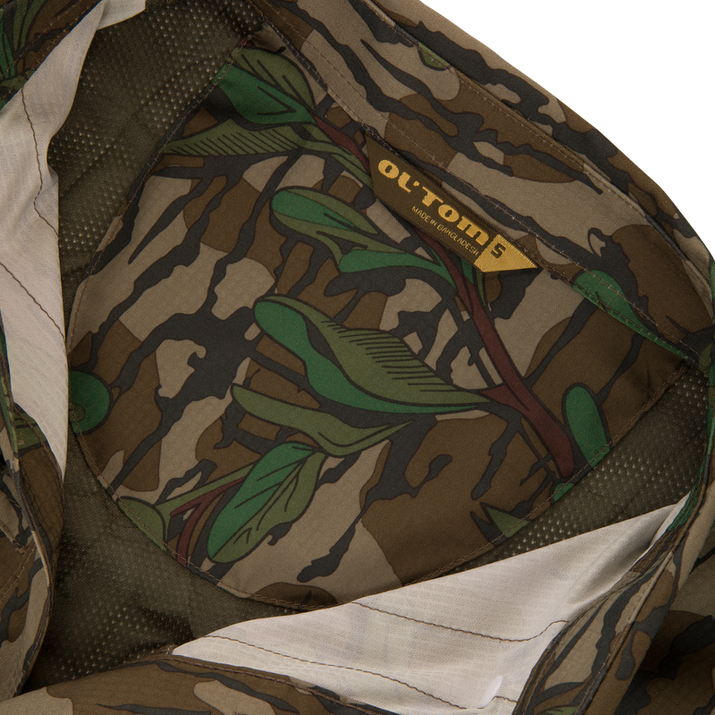 Men's Camo Wingshooter Trey Shirt, featuring a close-up of its camouflage fabric, highlighting the label and logo, emphasizing high-performance, moisture-wicking, and sun-protection features.